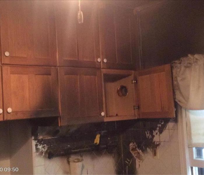 Fire damage on kitchen cabinets and microwave. 